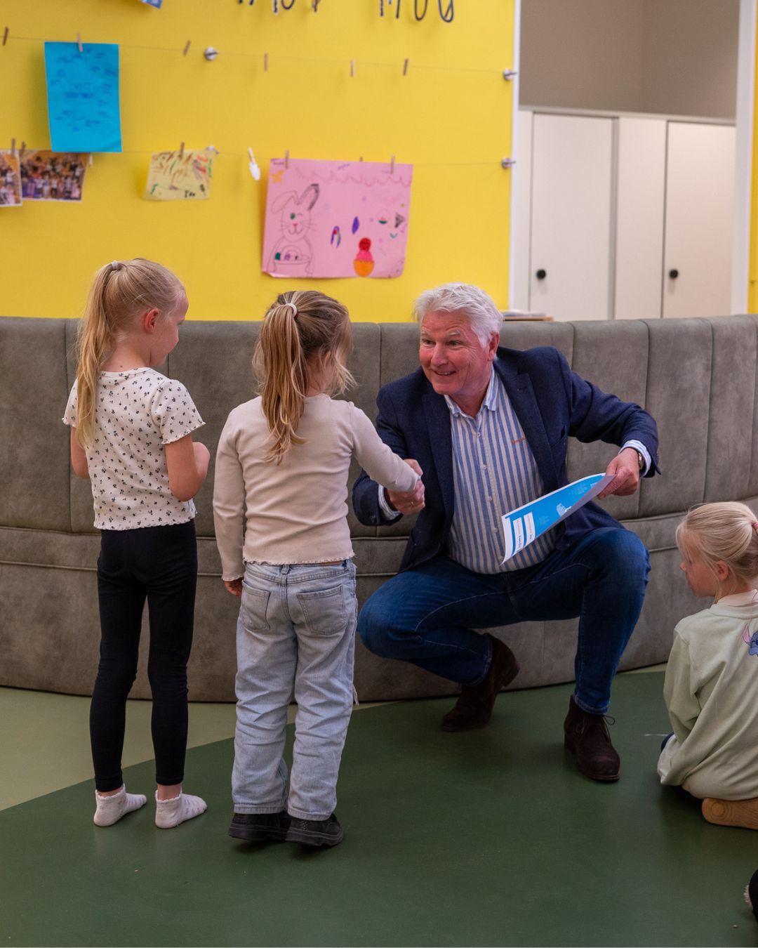 cheque overhandiging. kinderen overhandigen cheque aan man. man zit gehurkt op knieën.
