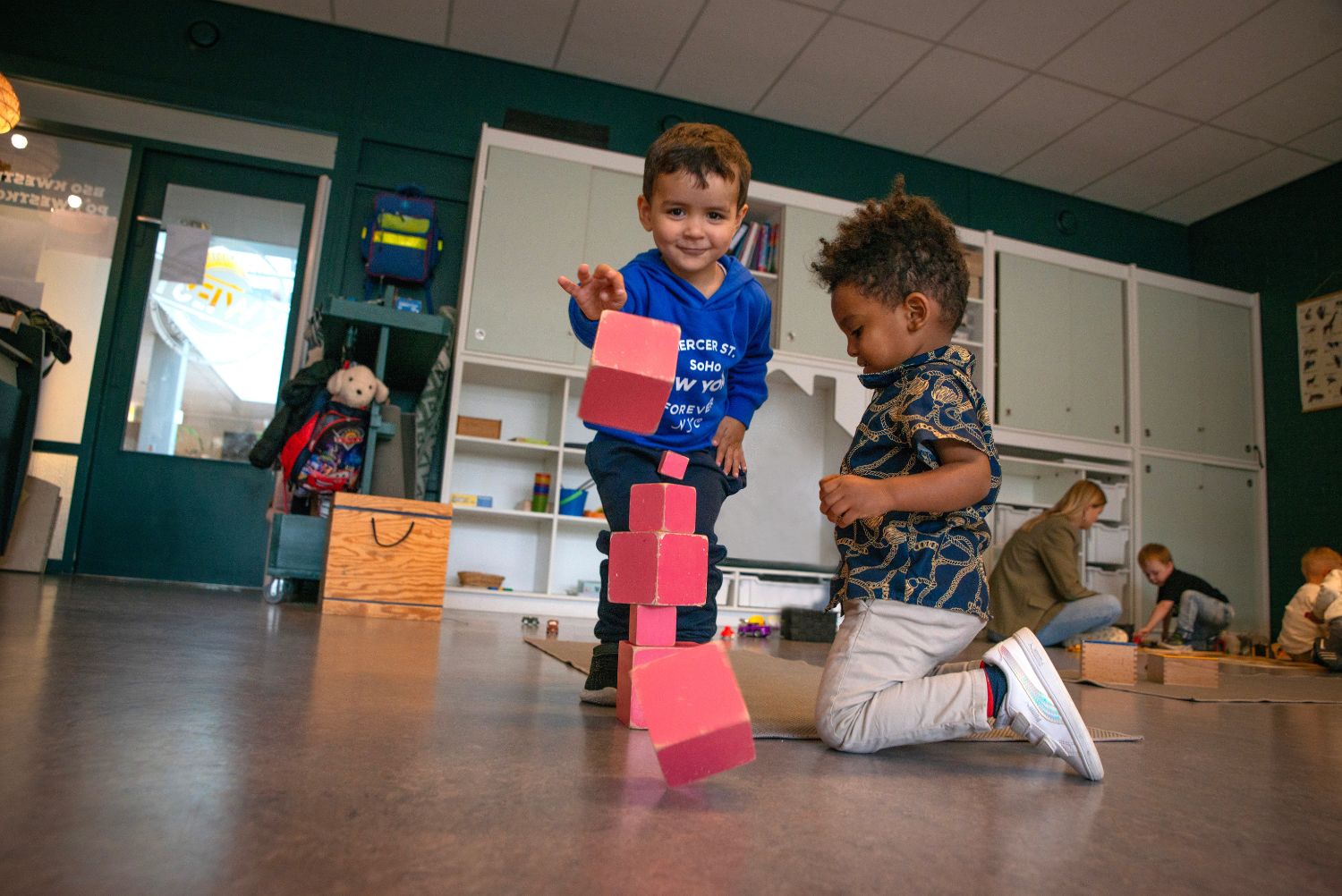 twee peuters spelen met een roze blokkentoren van Maria Montessori
